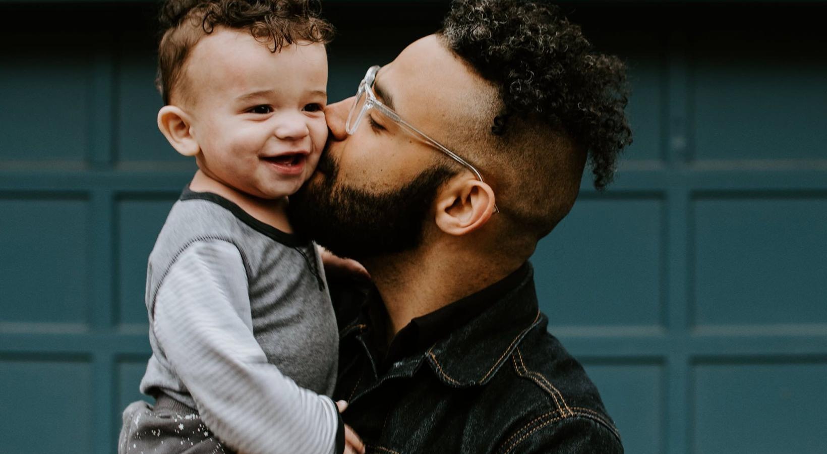 A perfect fit for the whole family father holds and kisses his toddler son