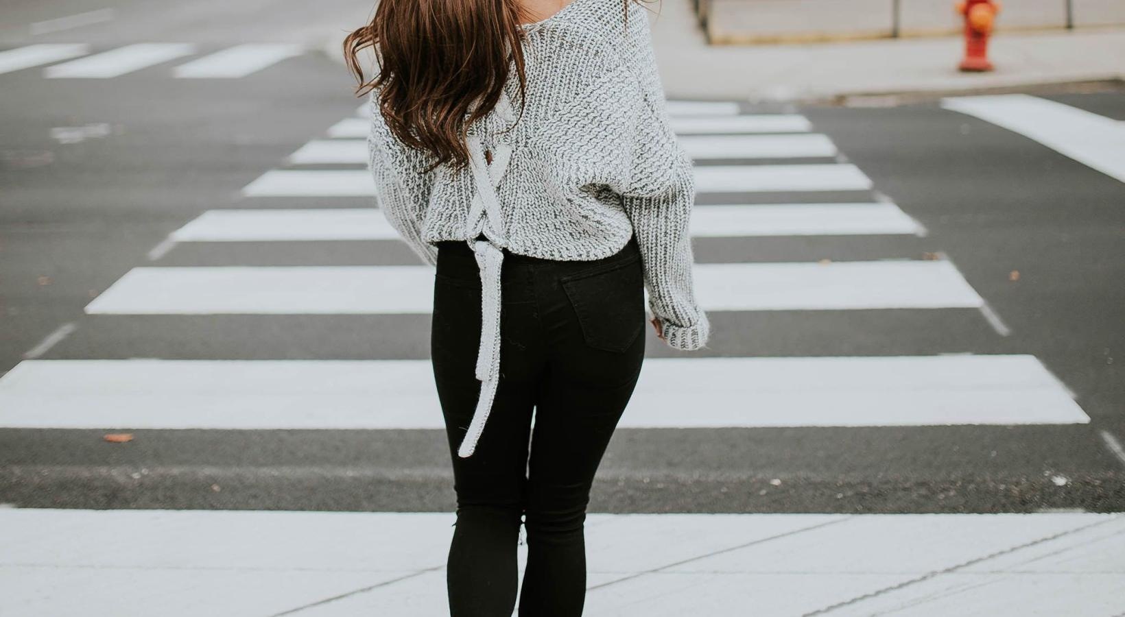 Close to the center of everything a person walking in a crosswalk