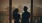 a man and woman standing next to each other and looking out a window