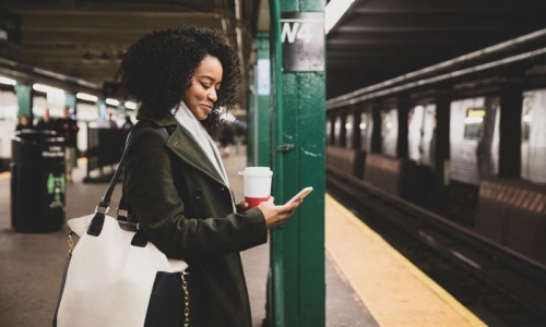 Find your perfect fit at Eight O Five woman with a cup of coffee texts on subway station platform