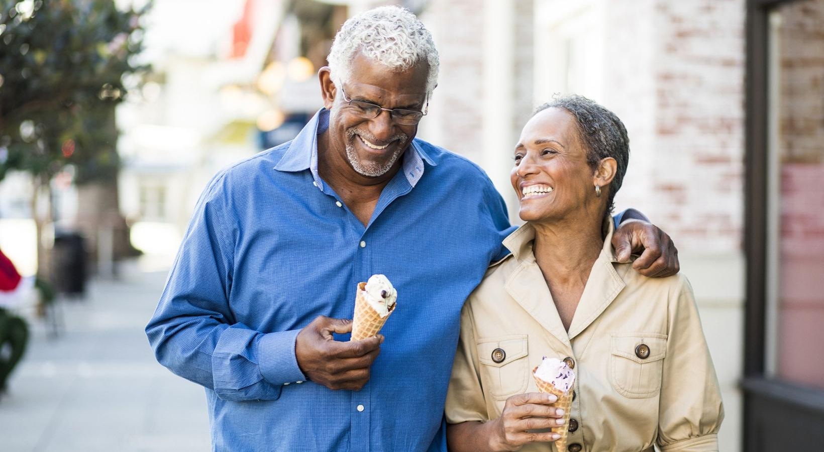 Close to the center of everything older couple walks down city sidewalk while holding ice cream cones